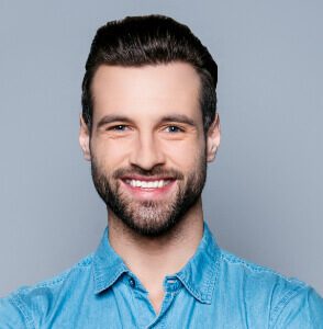 A man with a beard and blue shirt smiling.