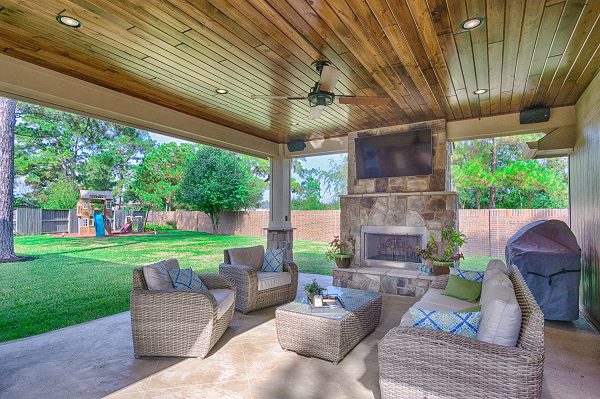 A covered patio with furniture and a fireplace.